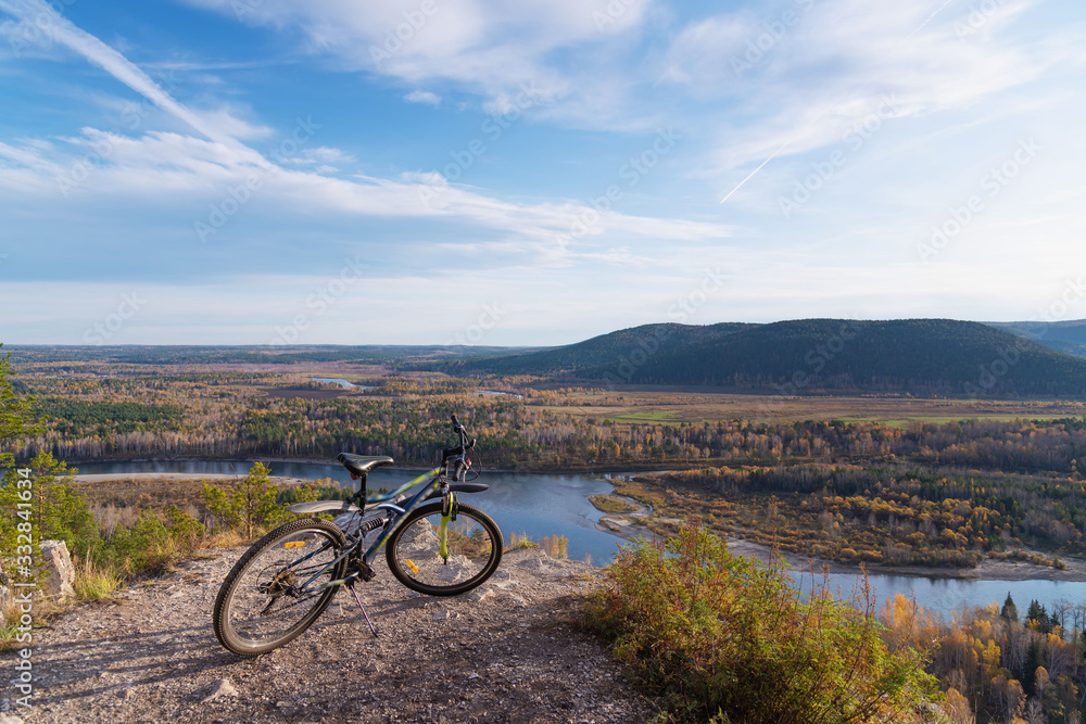 Obraz premium the bike is already on the trail with a view of the mountains and the river flowing in the valley, around the forest. the concept of tourism and a healthy lifestyle
