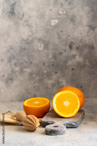 Fresh orange fruit on cut board with citrus squeezer.