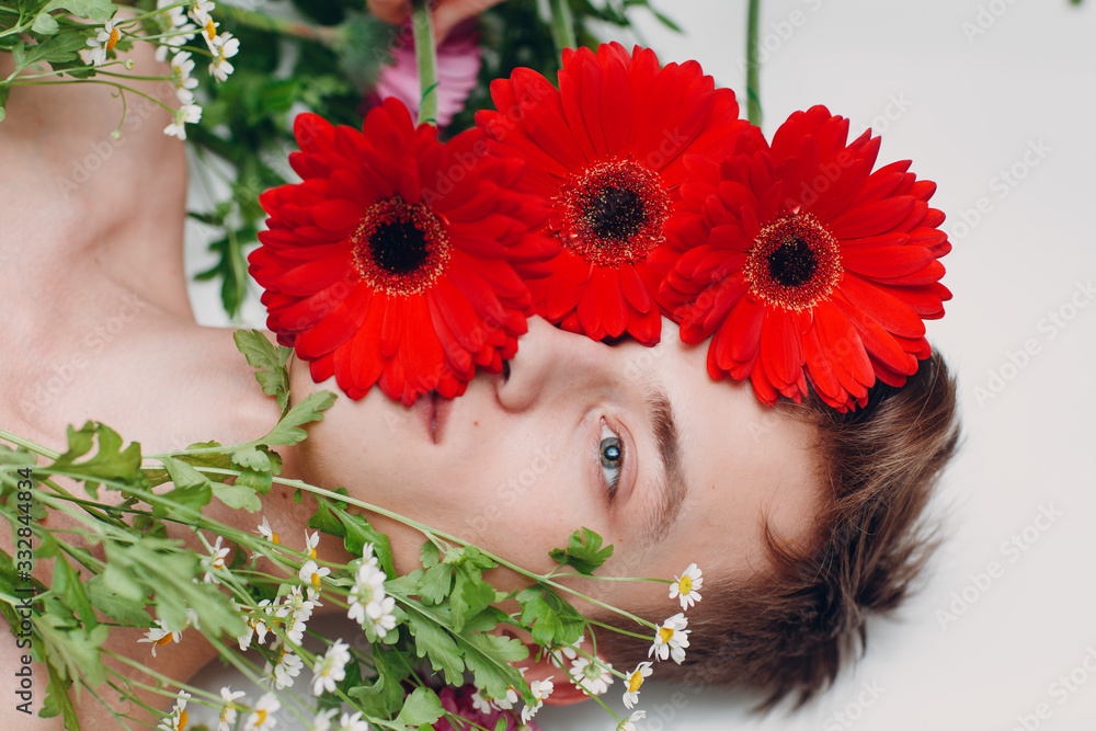 Young male model with flowers. Beauty portrait.