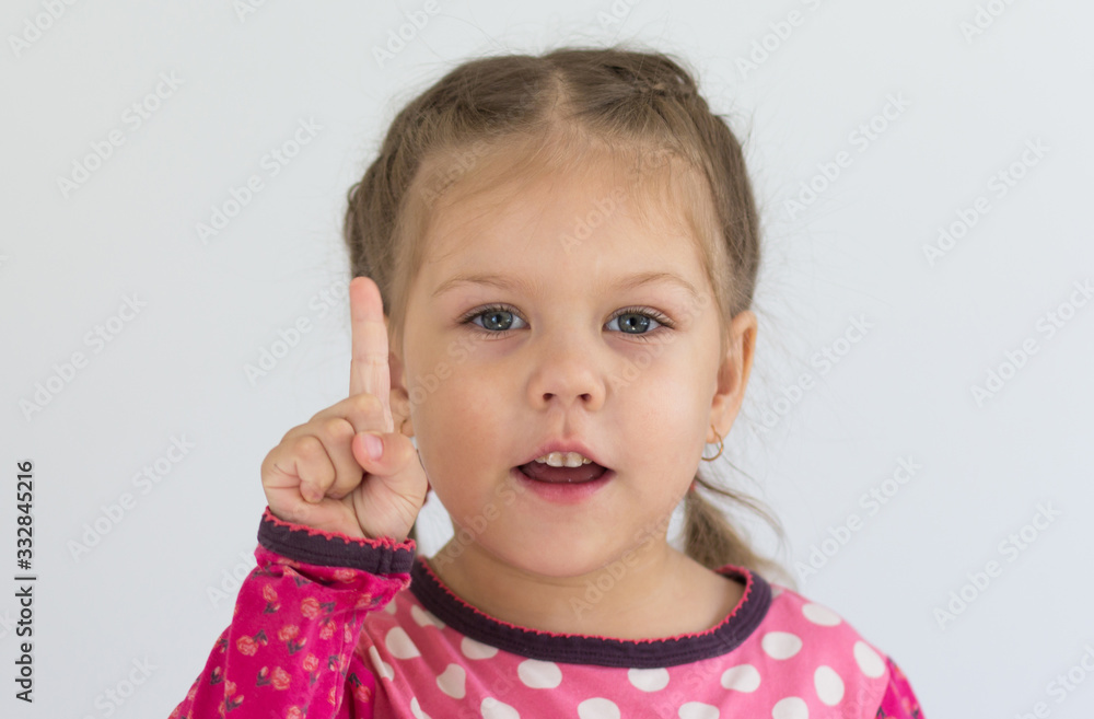 Portrait of caucasian child of three years old holding finger to show number one or telling importance looking at camera on the white background Portrait of caucasian child of three years old holding finger to show number one or telling importance looking at camera on the white background