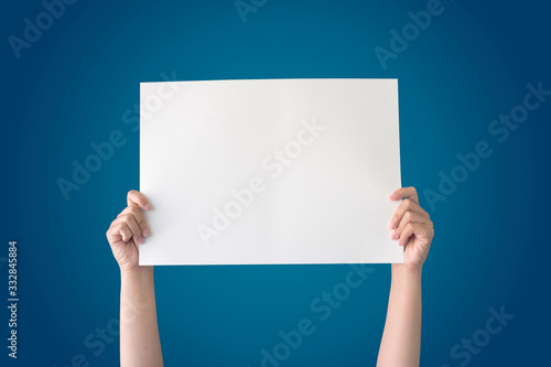 hand holding white blank paper isolated on blue gradient background with clipping path
