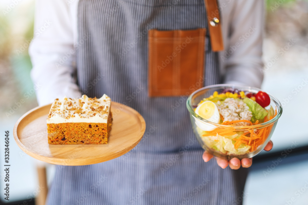 A waitress holding and serving a plate of carrot cake and a bowl of vegetables salad