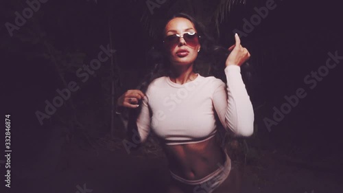 Cute and sexy brunette girl wearing pink long sleeve crop top and panties set and sunglasses dancing, smiling, flirting during summer evening - video in slow motion