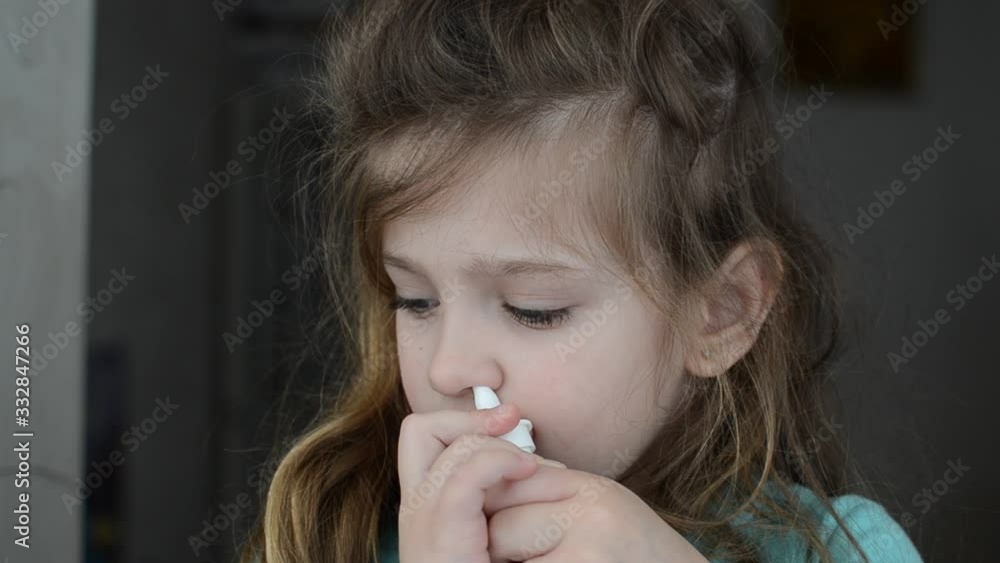 Little charming girl child sprays a runny nose spray in her nose Little charming girl child sprays a runny nose spray in her nose