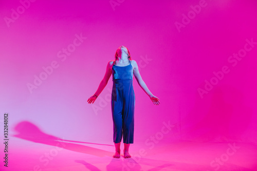 Young stylish girl dancing in the Studio on a colored neon background. Music dj poster design.
