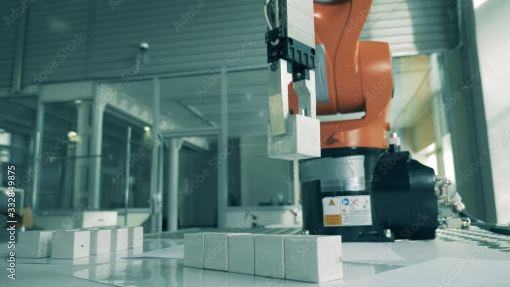 Robotic arm is transporting small objects at modern lab. Industrial robotic manipulator works with cubes. Robotic arm is transporting small objects at modern lab. Industrial robotic manipulator works with cubes.