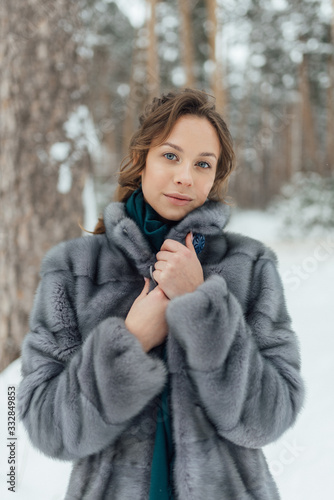 a beautiful girl in a wedding dress stands in a winter pine forest