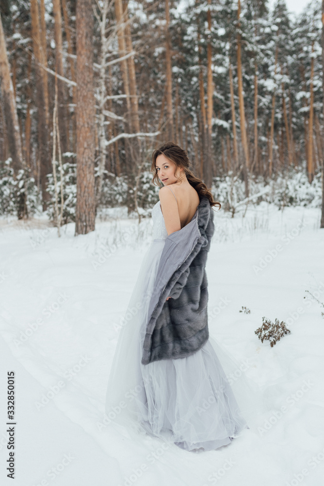 a beautiful girl in a wedding dress stands in a winter pine forest a beautiful girl in a wedding dress stands in a winter pine forest