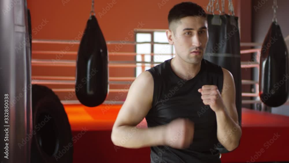 Professional male athlete punching the air in boxing gym and then standing and looking at camera Professional male athlete punching the air in boxing gym and then standing and looking at camera