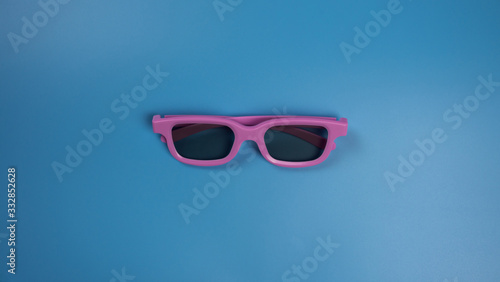 Pink 3D glasses for watching a movie on a blue background. Flatlay
