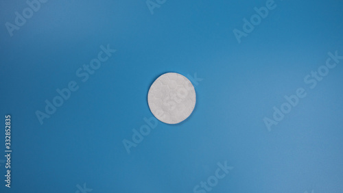 New cotton pad for removing makeup on a blue background with place for text