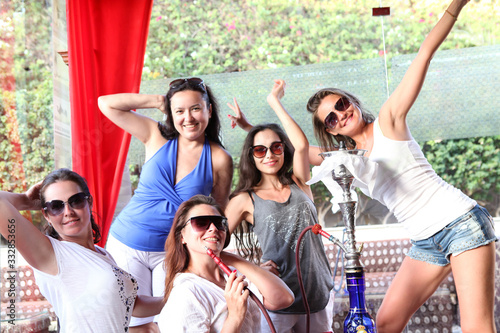 The company of young beautiful girls smokes a hookah. Smoke. The girl releases smoke. Tobacco.