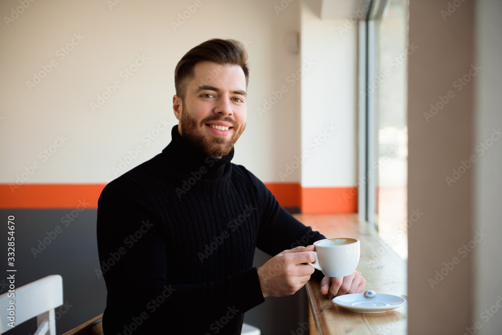 Attractive successful young businessman drinking coffee sitting at cafe table. Attractive successful young businessman drinking coffee sitting at cafe table.