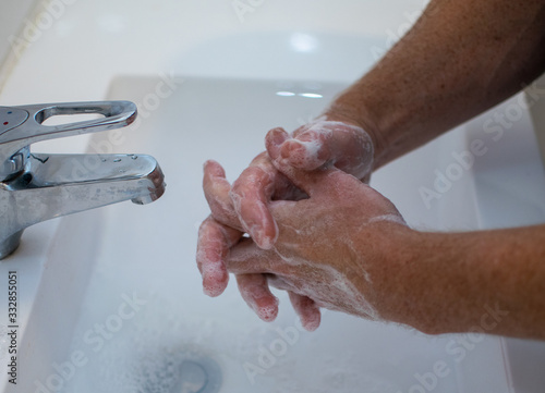 A man  is wahing his hands at the white sink in the bathroom.