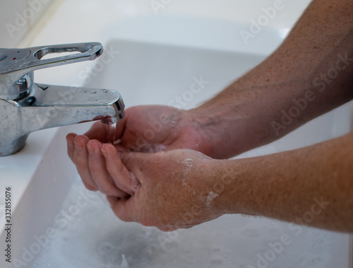 A man  is wahing his hands at the white sink in the bathroom.