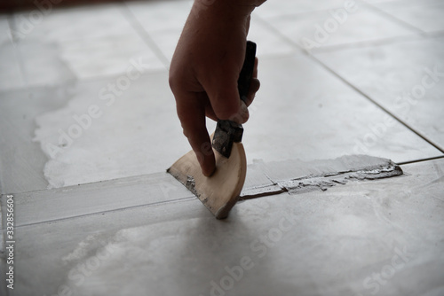 Tiler laying the ceramic tile on the floor. Professional worker makes renovation. Construction. Hands of the tiler. Home renovation and building new house photo