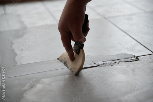 Tiler laying the ceramic tile on the floor. Professional worker makes renovation. Construction. Hands of the tiler. Home renovation and building new house
