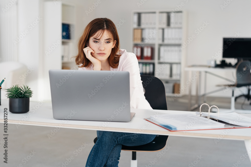 Young businesswoman staring glumly at her laptop Young businesswoman staring glumly at her laptop