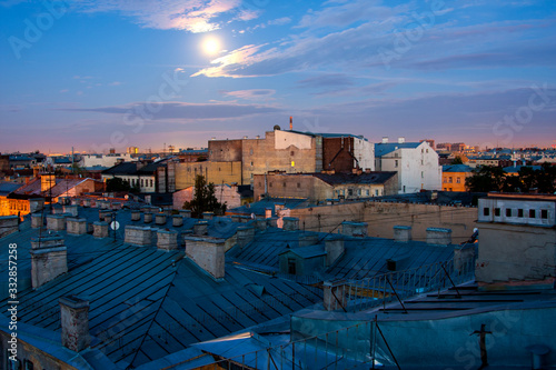 Roofs and walls against the sky with the moon