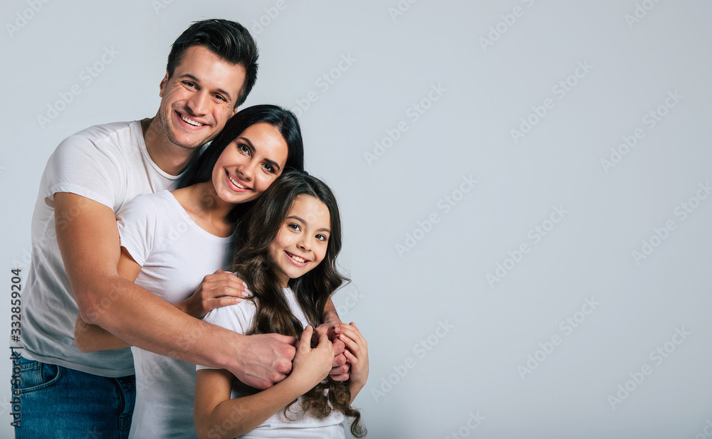 Beautiful excited and the funny family team is posing and pointing in a white t-shirt while they isolated on white background in studio. Beautiful excited and the funny family team is posing and pointing in a white t-shirt while they isolated on white background in studio.
