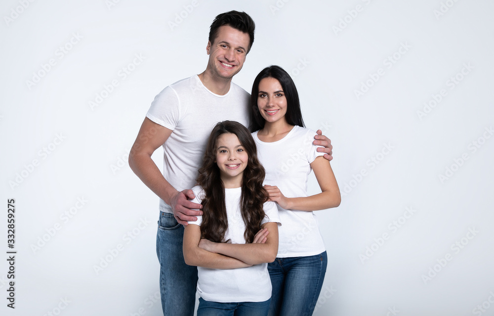 Beautiful excited and the funny family team is posing and pointing in a white t-shirt while they isolated on white background in studio. Beautiful excited and the funny family team is posing and pointing in a white t-shirt while they isolated on white background in studio.