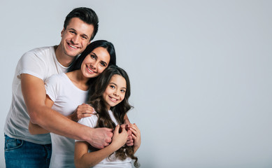 Beautiful excited and the funny family team is posing and pointing in a white t-shirt while they isolated on white background in studio.