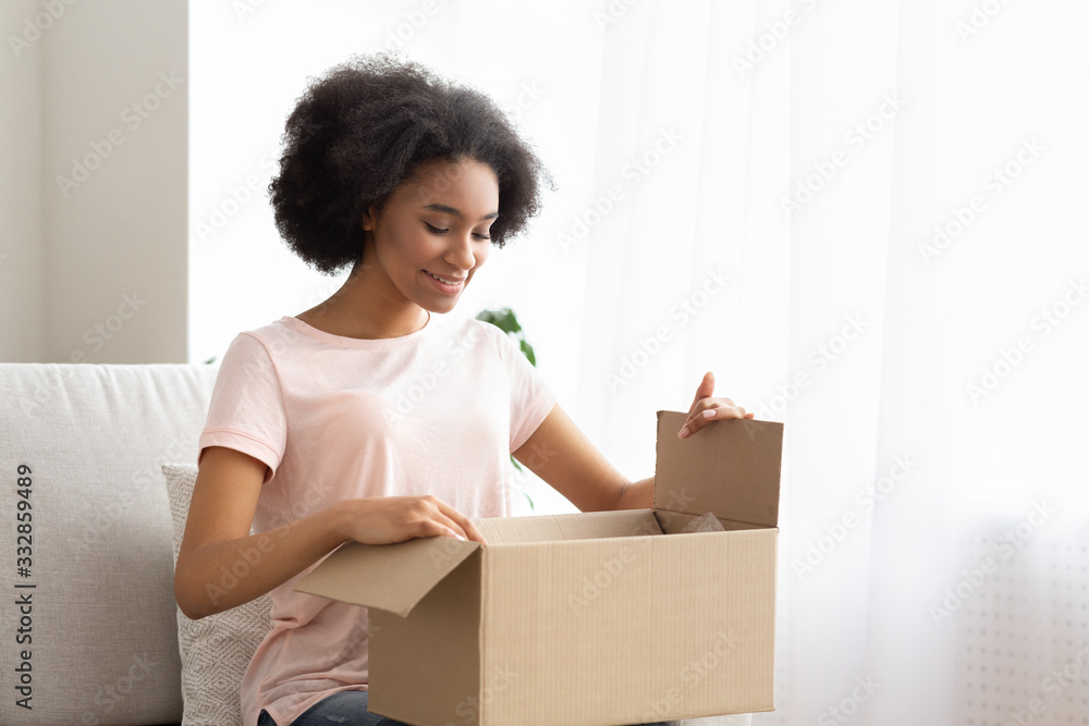 Satisfied young woman customer sit on sofa, unpack package parcel Satisfied young woman customer sit on sofa, unpack package parcel