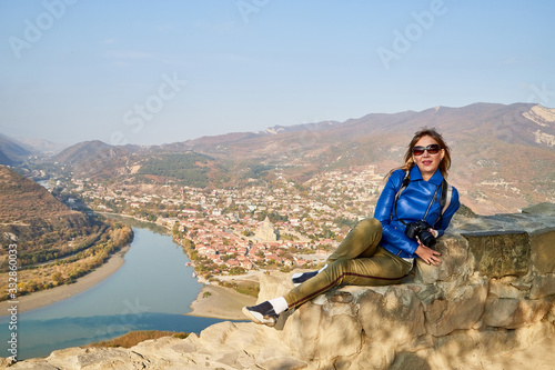 Attractive beautiful young girl who is female photographer traveller holding modern mirror camera in the hands outdoors in the mountains