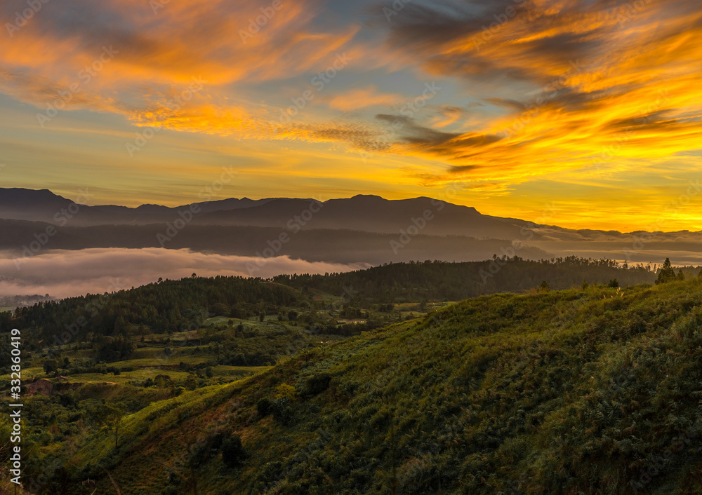 Bright golden sunrise Sea of clouds above Blangkejeren town but below impressive Bukit Barisan mountain range seen from Kedah, Banda Aceh while wild camping on a hill near Leuser ecosystem