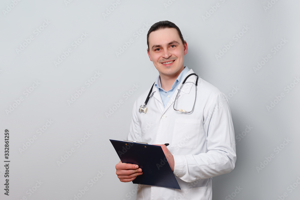 portrait of a young smiled doctor in a dressing gown, with a stethoscope and a clipboard. portrait of a young smiled doctor in a dressing gown, with a stethoscope and a clipboard.