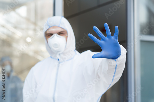 Man in virus protective suit and mask gesturing to stop world epidemic