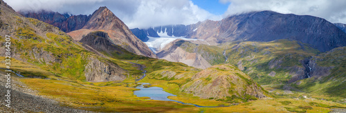 Panoramic view of the picturesque mountain valley. Morning light, snow-capped peaks and mountain steppe.