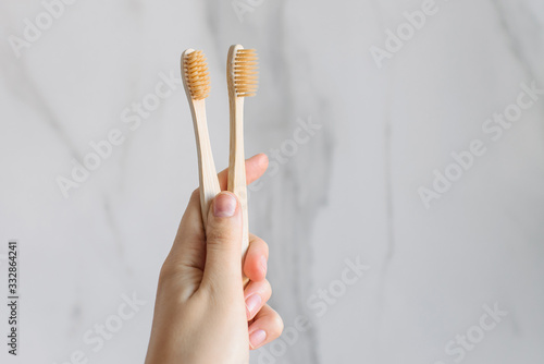 Eco-friendly wood and bamboo toothbrush on a bright white marble background in your hand. Stomatology.
