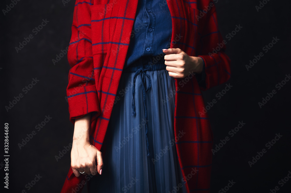 Hands of a young stylish girl in fashionable clothes of red and blue color.