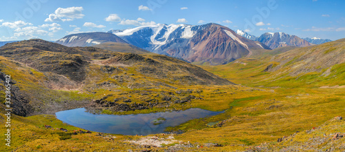 Panoramic mountain landscape. Lake in the valley and snow-capped peaks. Traveling in the mountains, trekking. © Valerii