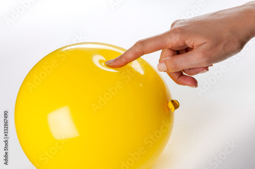 Finger pressing into a yellow balloon.