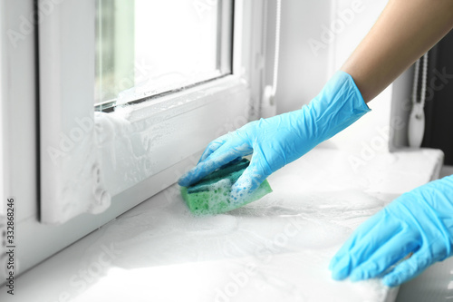Woman cleaning window sill with sponge, closeup