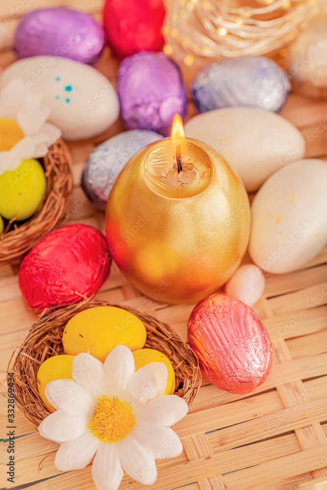 Festive easter concept of candle and colorful eggs on a wooden table. Daisy flower, green eggs in the nest. Greeting card Easter. Festive easter concept of candle and colorful eggs on a wooden table. Daisy flower, green eggs in the nest. Greeting card Easter.