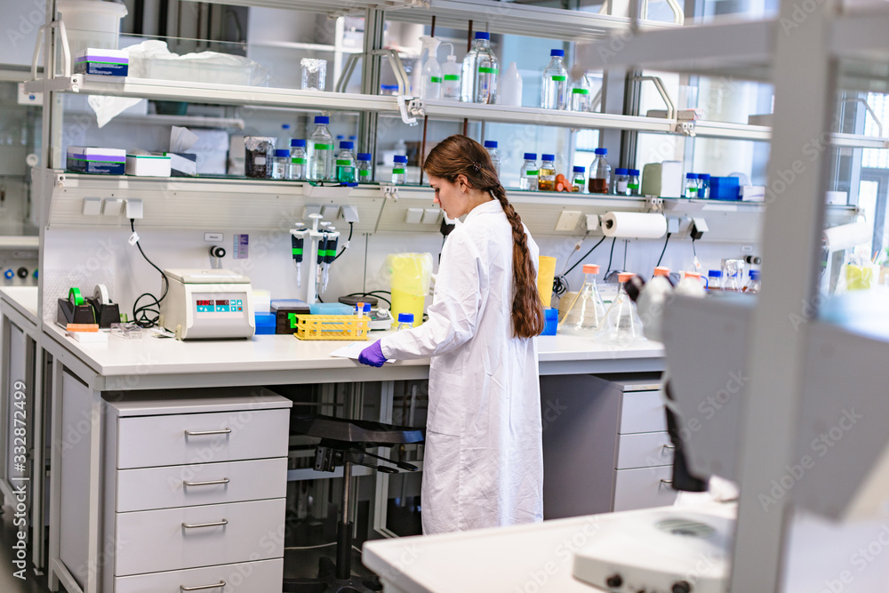 Girl scientist studying notes near lab equipment