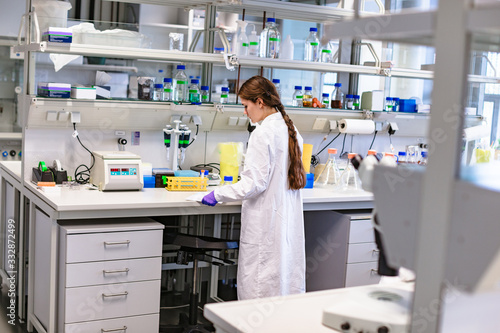 Girl scientist studying notes near lab equipment