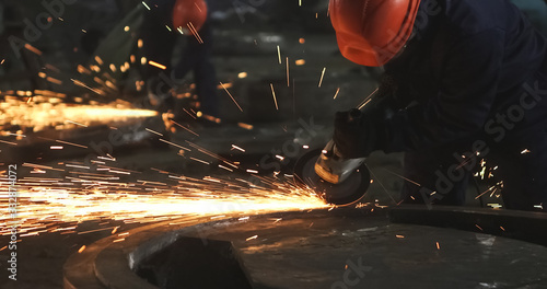 Working in a mask and headphones cleans joints angle grinder on metal parts blanks