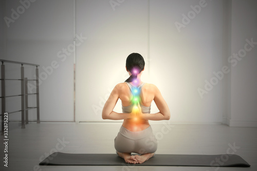 Photography Young woman with chakra points practicing yoga in studio, back view