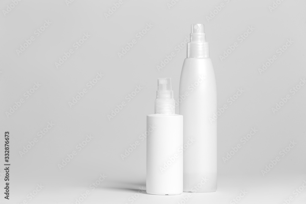 Set of cosmetic products in white and grey containers on light background.
