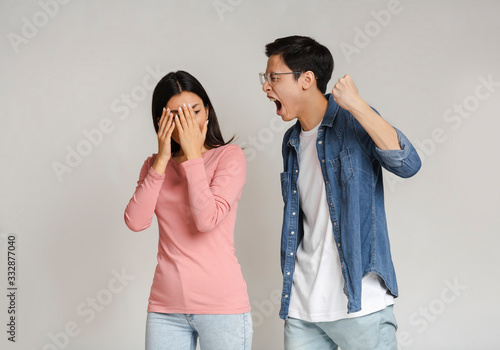 Violent asian man threatening his girlfriend with his fist outdoors