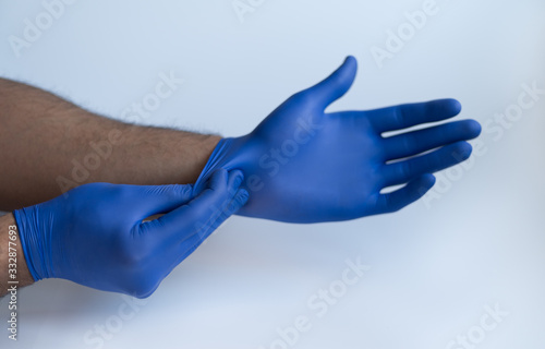 Male doctor hands wearing nitrile blue medical protection gloves. Front view photography on white studio background. 