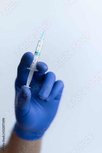 Male doctor hand holding a syringe with vaccine from virus ready to give injection. Front view photography on white studio background. 