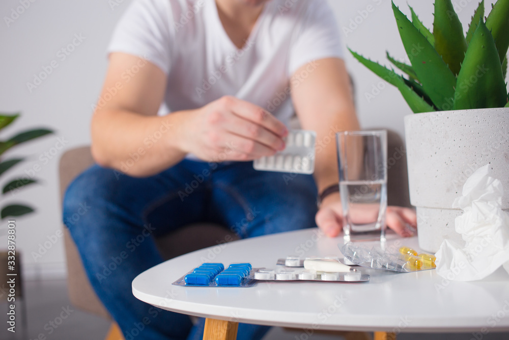 Man taking his pills on couch in the living room Man taking his pills on couch in the living room