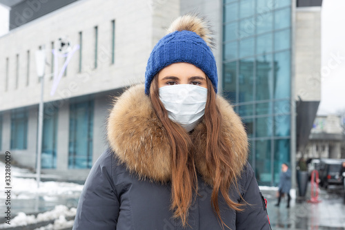 Portrait of woman walking down the street in winter in a protective mask to protect against infectious diseases. Protection against colds, flu, air pollution. Health concept © simikov