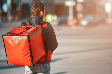 Сontactless food delivery to customers home. Delivery service worker with thermal backpack quick delivering food at doorstep in quarantine from restaurant, supermarket or cafe . Online ordering food