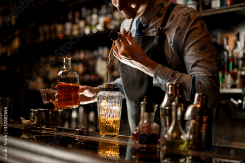 bartender using beaker carefully pours drink into glass shaker